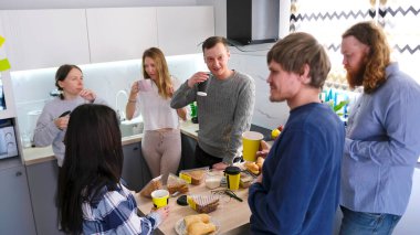 Şirket çalışanları ofis mutfağında yemek yer ve kahve içerler. Bir grup insan sohbet etmek için bir mutfak adasının etrafında toplanıyor. İnsanlar birbirlerine eşlik etmekten hoşlanırlar.