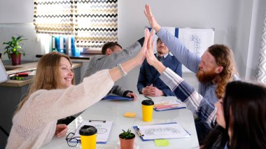 Bir grup neşeli insan bir konferans odasında coşkuyla birbirleriyle sohbet ediyorlar. Meslektaşlar beşlik çakıyor. Atmosfer olumlu ve dost canlısı.