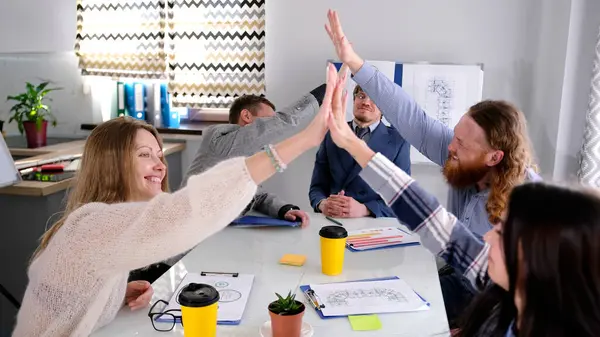 Bir grup neşeli insan bir konferans odasında coşkuyla birbirleriyle sohbet ediyorlar. Meslektaşlar beşlik çakıyor. Atmosfer olumlu ve dost canlısı.