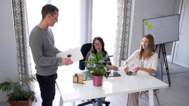 Bilgisayarlı genç bir adam halkla ilişkiler müdürünün ofisine girdi. İki güzel kadın bir masada oturmuş sabah haberlerini tartışıyorlar..