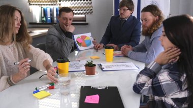 Profesyonel pazarlama uzmanlarından oluşan bir grup toplantı odasında bir masada oturmuş ciddi bir görev üzerinde düşünüyor. Aile ofisinde takım çalışması..