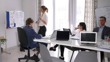 Bir grup finansör bir konferans odasında beyaz bir pano ve birkaç dizüstü bilgisayarla birlikte. Sahne profesyonel ve odaklanmış. Kârlılık ve yeniden yapılanma