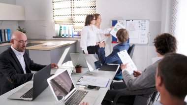 İki kadın, şirketin kalkınma ve sorunlu alanları için kaynak bulma ve kalkınma için yeni göstergeler planlama konulu bir sunum yapıyor. Ekonomistler Toplantısı