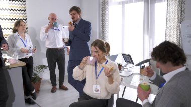 İşte bir mola. Şirketin çalışanları ofiste öğle yemeği yiyorlar. Bir grup iş adamı sandviç yiyor ve kahve içiyor. Kahve molası