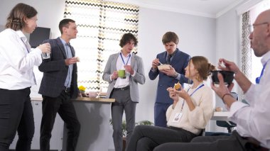 Meslektaşlar şirketin konferans salonunda öğle yemeği yiyorlar. Bir grup kadın ve erkek salata yiyor, sandviç yiyor ve kahve içiyorlar. İş yemeği. Kahve molası