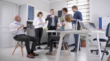 Şirket personeli öğle yemeğini ofiste yemeye karar verdi. Hepsi iş kıyafetleri içinde, ellerinde kahve ve salata bardakları var. Bir grup insan konferans odasındaki masanın etrafında toplandı..