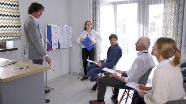 Yakışıklı bir profesyonel danışman genç bir finans şirketi için iş eğitimi veriyor. Takım oluşturma. Takım çalışması. Profesyonellik ve işbirliği ruhu