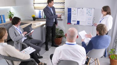 Şirketin müdürü elinde bir işaretçiyle bir sunum yapıyor. İşbirlikçi ve maksatlı iş, grup birlikte çalışır, fikirleri tartışır ve kararlar alır..