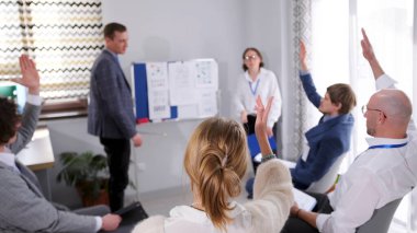 Konferansta bir soru sor. Seyirciler bir iş eğitimi dersinde ellerini kaldırdılar. Bir grup insan sunum kurulunun etrafında toplandı. Hepsi özenli ve tutkulu..