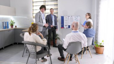 Toplantı küçük bir danışmanlık şirketinin müdürü tarafından düzenlendi. Bir grup insan şirketin geliştirme stratejilerini tartışıyor. Sahne kasıtlı bir iştir.