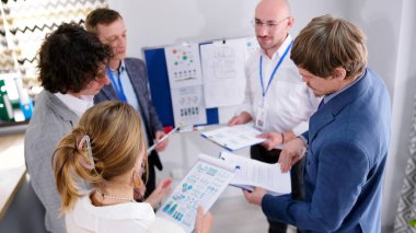 Bir grup finansçı bir çember oluşturup satış raporunun detaylarını tartıştılar. İş adamları çözümler ve stratejiler geliştirmek için birlikte çalışırlar. İş Ofisi