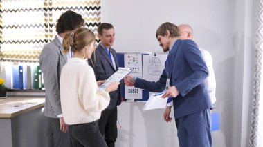 Bir grup ofis çalışanı toplantıdan önce birbirlerini selamlarlar. Takım elbiseli iki adam el sıkışıyor. Takım oluşturma. Takım çalışması. Brifing için hazırlıklar.