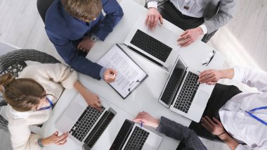 Bir grup insan açık dizüstü bilgisayarları ve kağıt sözleşmesi olan bir masada oturuyor. Takım çalışması. Beyin fırtınası seansı. Takım oluşturma. Bilgilendirme