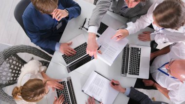 Bir grup girişimci, kârlı bir anlaşma olan üst görüş üzerinde anlaşmaya vardılar. Şirketin avukatı, finansörü ve muhasebecisi dizüstü bilgisayarlarla bir masada oturuyor ve bir proje üzerinde birlikte çalışıyorlar.