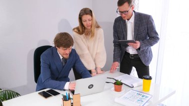 İki meslektaşı müdürün masasında dizüstü bilgisayarına bakıyor. Takımda dostane bir atmosfer var. İş adamları büyük bir projeyi tartışıyorlar..