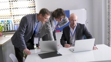 Şirketin üç kurucu ortağı dizüstü bilgisayarlarındaki satış istatistiklerine dikkatlice bakıyorlar. Bir grup başarılı adam şirketin yeniden yapılandırılmasıyla ilgili çalışmaları tartışıyor.