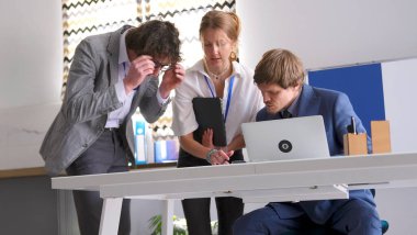 Beyin fırtınası seansı. Üç girişimci anlaşmanın ayrıntılarını tartışıyorlar. Gözlüklü bir adam, bir kadın ve mavi takım elbiseli bir adam ortak bir proje üzerinde çalışıyorlar. Takım çalışması..