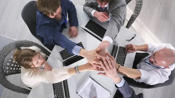 Bir avukat şirketi zaferini üst düzey bir duruşmada kutluyor. Takım oluşturma. Takım çalışması. Bir grup insan dizüstü bilgisayarlarla bir masada oturuyor ve ellerini sıkıyor.
