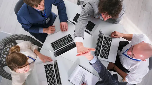 İki meslektaş müzakere masasında otururken birbirlerine beşlik çakıyorlar. Bir grup insan laptoplarla dolu bir masada çalışıyor. Pozitif ve dostane bir atmosfer
