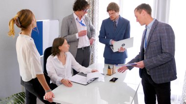 Başarılı ve umut verici bir şirkette çalışmak. Bir grup insan önemli bir projeyi tartışıyor. İşadamları, bazılarının ellerinde dizüstü bilgisayarlarla baş masasının etrafında toplandı..