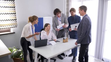 Şirketin birkaç çalışanı konferans odasında bir masada toplandı. Bir projeyi tartışıyorlar ve adamlardan birinin elinde dizüstü bilgisayar var. Takım çalışması. Takım oluşturma. Beyin fırtınası.