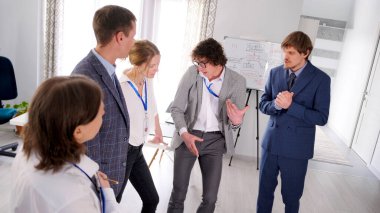 Bir grup genç girişimci bir konferans odasında duruyor. Takım oluşturma, takım çalışması, beyin fırtınası. Takım çalışması süreçleri oluşturuluyor. Danışmanlık firması.