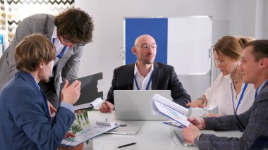 Şirketin kurucularıyla toplantı. Yöneticiler toplantısında sabah planlama oturumu. Bir grup başarılı, kendine güvenen ofis çalışanı bir masa başında dizüstü bilgisayar ve kağıtlarla oturuyorlar.