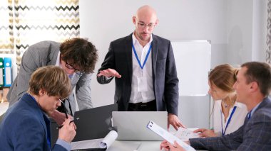 Başarılı, cana yakın, gözlüklü bir patron konferans odasında bir masada durup astlarına talimatlar verir. Şirket çalışanları masaya oturur ve onu dikkatle dinler.