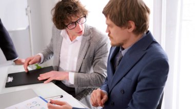 İş adamları toplantı odasında iletişim kurar. Bir danışmanlık firmasında brifing. Takım elbiseli iki adam bir masada oturuyor. Adamlardan biri gözlük takıyor ve diğeri kravat takıyor..