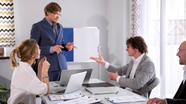 Konferans odasında iki adam arasındaki iş diyaloğu. Yönetmenler toplantısı. Bir grup ofis çalışanı toplantı odasında bir masada oturmuş projenin detaylarını tartışıyorlar. Adam gruba seslenir ve...