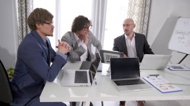 Bir konferans odasında üç iş adamı. Önlerinde dizüstü bilgisayarlar ve önemli belgeler olan bir masada üç adam oturuyor. Büyük bir projede çalışmanın detaylarını tartışıyoruz..