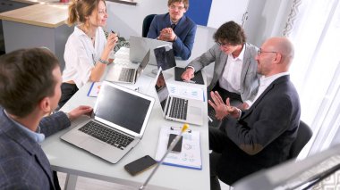 Patron, şirketin tüm departmanlarının müdürlerini toplantıya çağırdı. Bir grup insan dizüstü bilgisayarları ve kağıtları olan bir masada oturuyor. Önemli bir şeyi tartışıyorlar..