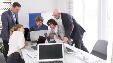 Şirket personeli dizüstü bilgisayarlar ve kağıtlarla dolu bir masanın etrafında toplandı. Toplantı konferans odasında. Sabah planlama seansı. Bir girişim başlatılıyor. Ekip önemli bir projeyi tartışıyor.