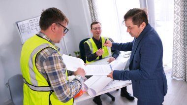 Şık, kendine güvenen, başarılı bir iş adamı müteahhitlerden bir fiyat imzalar. Üç adam bir nesnenin yapımını tartışıyor. Baş mühendisin ofisinde..