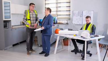 Baş mühendis ve baş mühendis mimarın ofisinde inşaat projesinin detaylarını tartışıyorlar. Mimarlık bürosunun samimi bir aile ofisi..