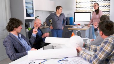 Mimarlık bürosunun personeli modern mimari bir nesnenin inşa aşamalarını tartışıyor. Bir grup insan sıcak bir aile ofisinde brifing için toplandı..