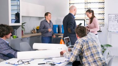 Bir mimarlık firmasının çalışma günleri. Brifing, takım çalışması. Bir grup insan rahat bir ofisteki masanın etrafında toplanıp proje planlarını tartışıyor. İşbirliği ve konsantrasyon atmosferi