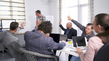 Bir adam yeni bir mimari proje sunuyor ve şirket personeli onun fikirlerini reddediyor. Bir grup insan konferans odasında bir masanın etrafında toplandı. Sahne çok enerjik.