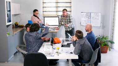 Baş mühendis inşaat şirketinin personelinin sorularını yanıtlıyor. Mimari bir projenin sunumu. Bir grup işadamı toplantı odasında bir masada oturuyor.