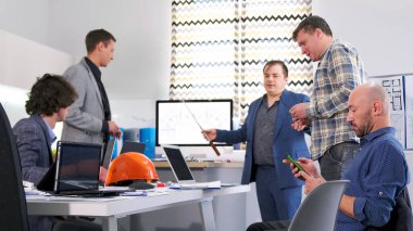 Bir grup erkek, modern bir iş merkezinin mimari tasarımı hakkındaki çalışmaların ayrıntılarını tartışmak için konferans salonunda toplandı. Sahne profesyonel ve odaklı, erkekler birlikte çalışıyor.