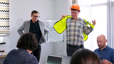 Turuncu şapkalı bir adam yeşil bir inşaat yeleği giyiyor ve inşaat kalite kontrolü için tesise girmek üzere. Mimarlık Bürosu. Çalışma günleri