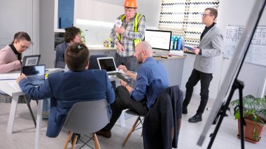 Ustabaşı masraflar için patrondan para ister. İnşaat mühendisi yönetim kurulu tarafından onaylanmak üzere bina planını getirdi. İş adamları konferans odasındaki bir masanın etrafında toplandılar..