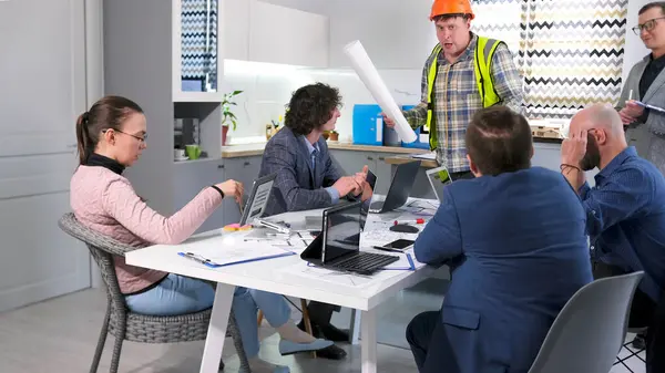 Ustabaşı ile inşaat şirketinin yönetimi arasındaki tartışma. Mimarlık bürosundan bir grup insan konferans odasında bir masada oturmuş proje tahminlerini tartışıyorlar..