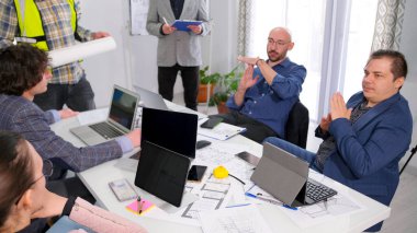 Müşterinin iki iş adamı, mimari bir nesnenin yapımını koordine etmek için bir toplantıda mola istiyor. Bir grup insan dizüstü bilgisayarlar ve kağıtlarla bir masanın etrafında toplandı..