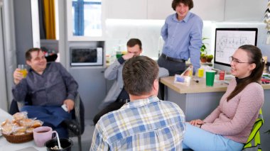 Kahve molası. Mutlu insanlar öğle yemeğinden sonra ofis mutfağında öylesine sohbet ederler. Bir grup insan birbirine eşlik etmekten ve yiyecek ve içecekleri paylaşmaktan zevk alıyor. Atmosfer dost canlısı.