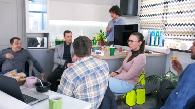 İnşaat şirketinin çalışanları ofis mutfağında bir masada oturuyor, yemek yiyor, kahve içiyor ve konuşuyorlar. Sahne rahat ve dost canlısı, ve insanlar birbirlerinin arkadaşlığından hoşlanıyorlar..