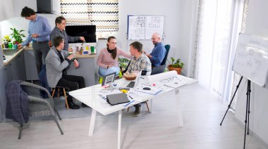 Mimarlık bürosundan meslektaşlar konferans odasında bir kahve molası düzenlediler. Bir grup insan aile ofisinin rahat mutfağında bir masada oturup yemek yiyorlar. İş yemeği.