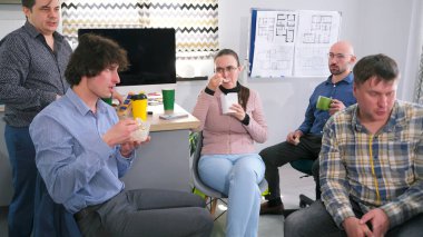 Bir grup yönetici konferans odasında oturuyor, bazıları kahve içiyor, diğerleri salata yiyor. Olay yeri sakin, meslektaşlar sohbet etmek ve arkadaşlığın tadını çıkarmak için bir araya geldiler..