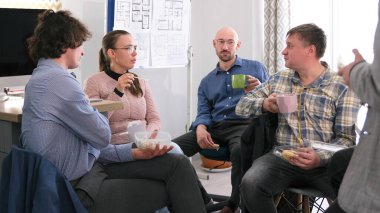 Arkadaşlar ve iş arkadaşları ofiste öğle yemeği yiyor ve birbirleriyle sohbet ediyorlar. Erkekler ve kadınlar salata yer ve çay içerler. İnsanlar birbirlerinin arkadaşlığından zevk almak için bir araya gelirler.