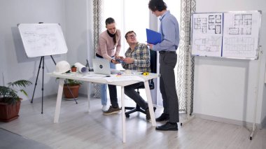 Küçük mimar danışmandan tavsiye ister. Kadın sekreter, patronun imzalaması için tablet getirdi. Odanın modern ve profesyonel bir atmosferi var..